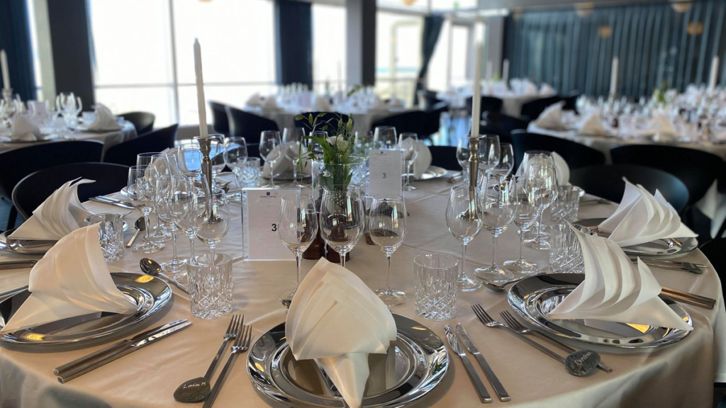 Opdækket bord med sølvtøj og blomsterdekorationer til en stor fest hos Montra Hotel Skaga