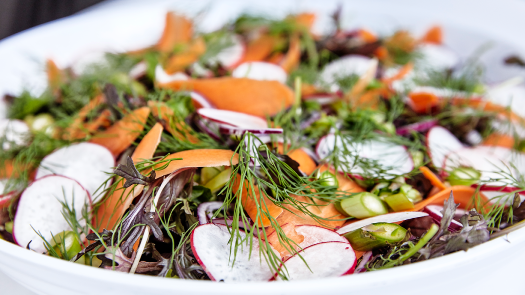 Lækker salat med radiser, gulerødder og forårets grønt serveret i skål på Montra Hotel Skagas restaurant hos